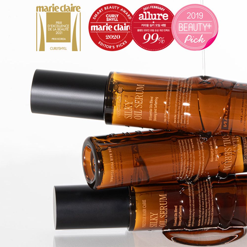 Tre flaconi di olio per capelli marroni con tappi neri. Scritta Silky Oil Serum. Sono visibili alcuni premi.