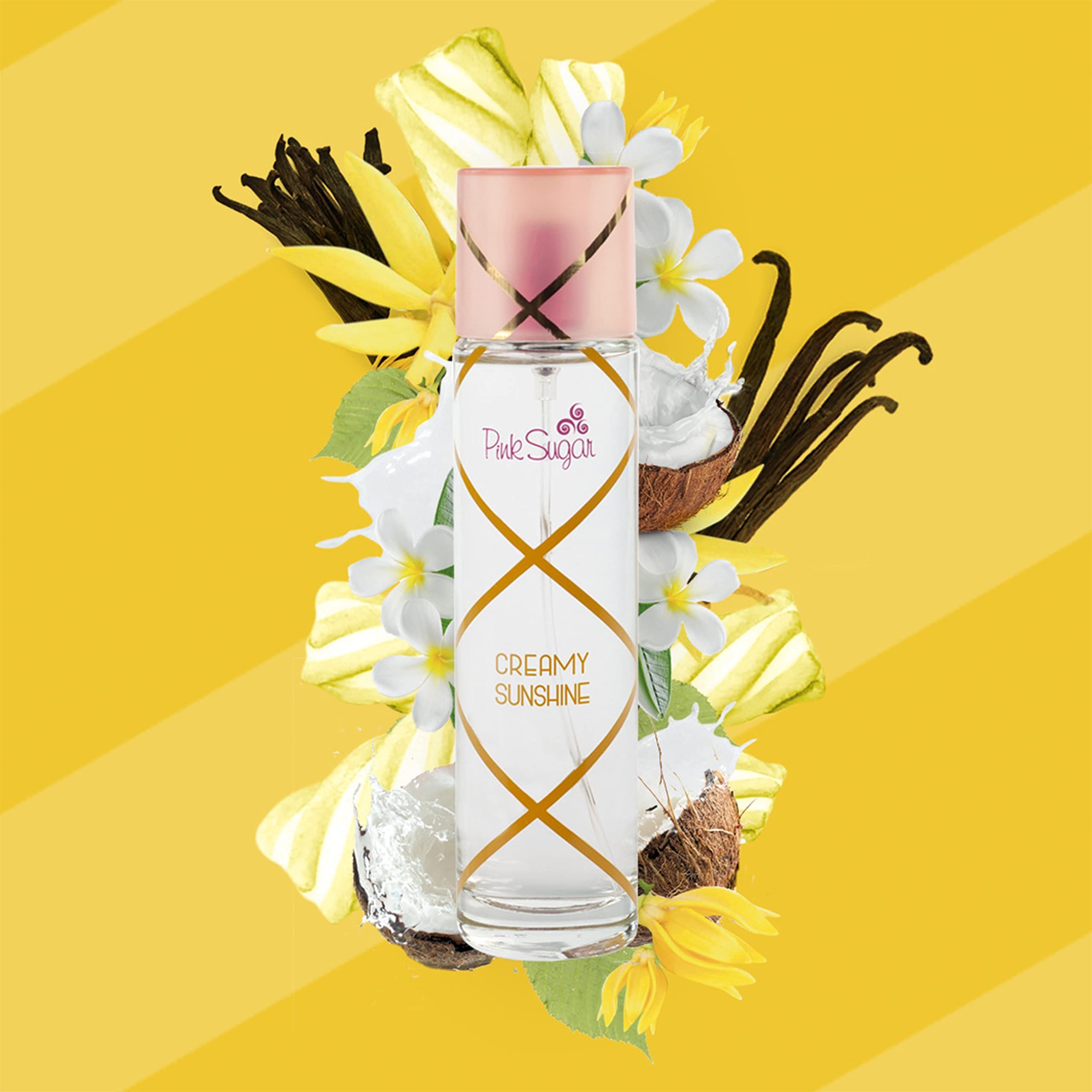 Flacone di profumo con tappo rosa, circondato da fiori e frutta. Scritta: Pink Sugar Creamy Sunshine.