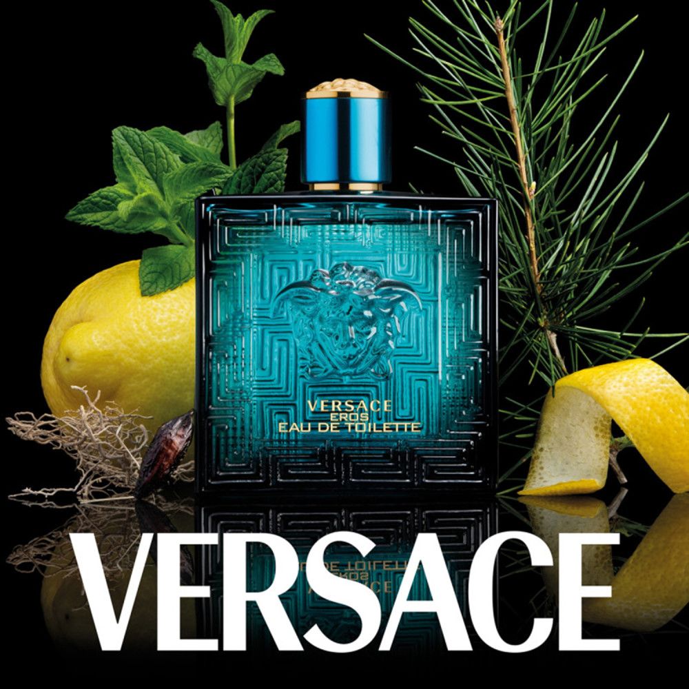 Flacone turchese Versace Eros con logo Medusa, circondato da limoni, erbe e ramoscelli di pino su sfondo nero.