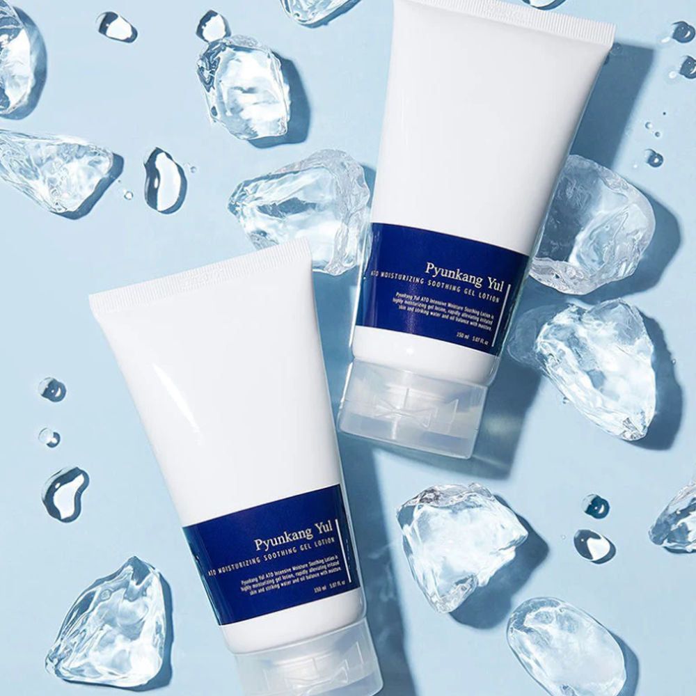 Due tubi bianchi con etichetta blu. Scritta: PYUNKANG YUL ATO Moisturizing Soothing Gel Lotion. Circondati da cubetti di ghiaccio e gocce d'acqua.