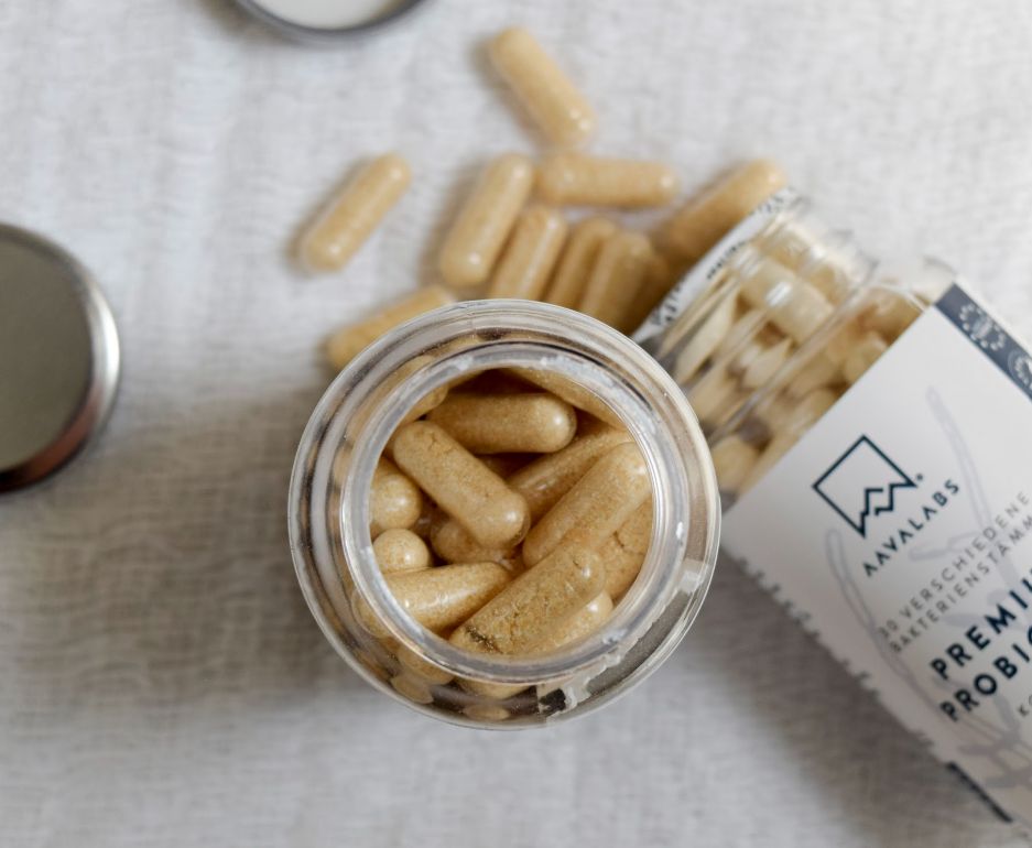 Capsule probiotiche Aavalabs fuori da un contenitore aperto, alcune sparse.