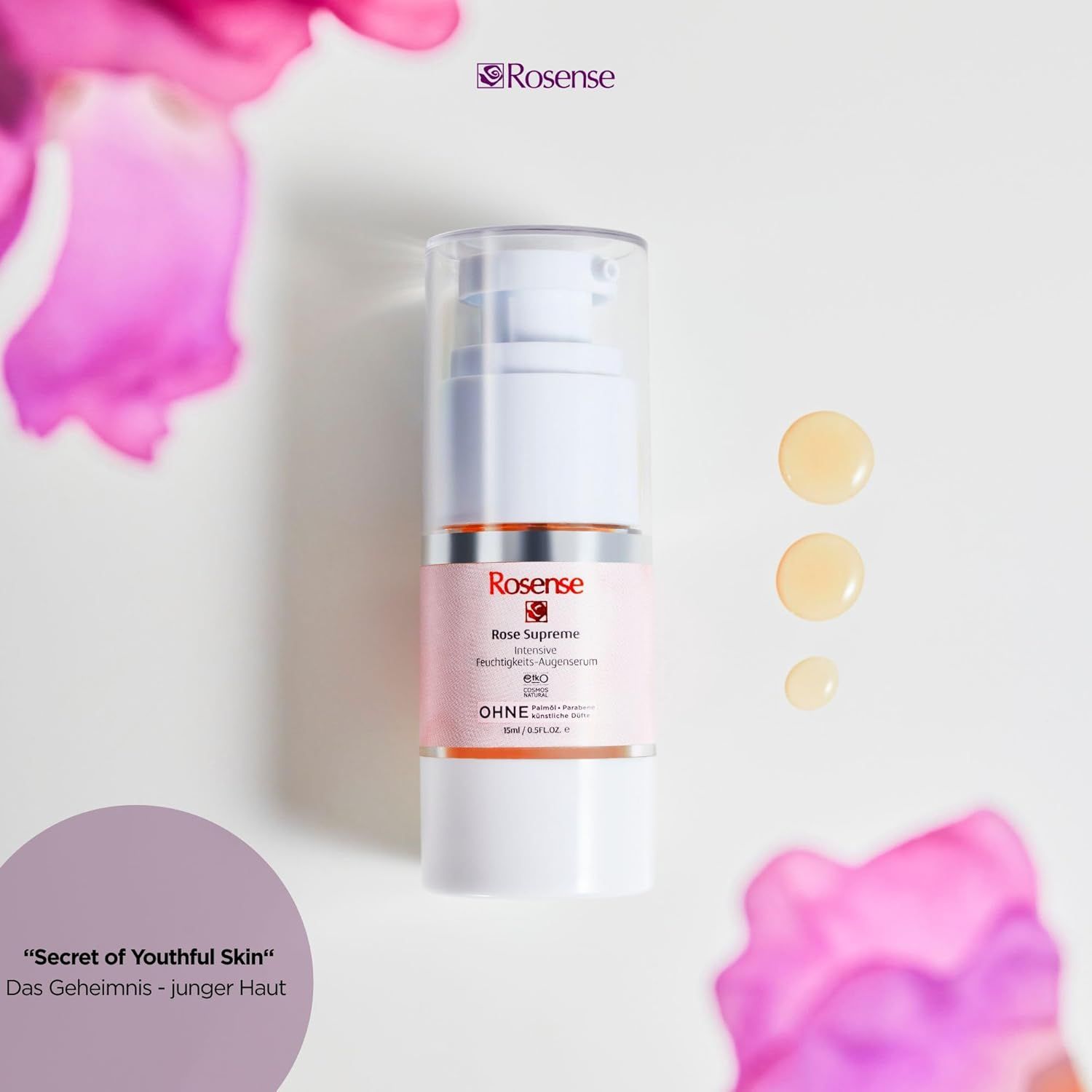 Dispenser bianco Rosense Supreme Augenserum con gocce. Etichetta rosa, testo. Sfondo: superficie bianca, fiori, testo.