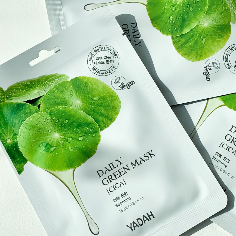 Confezione bianca con foglie verdi e gocce. Testo: DAILY GREEN MASK [CICA], YADAH, logo Vegan.