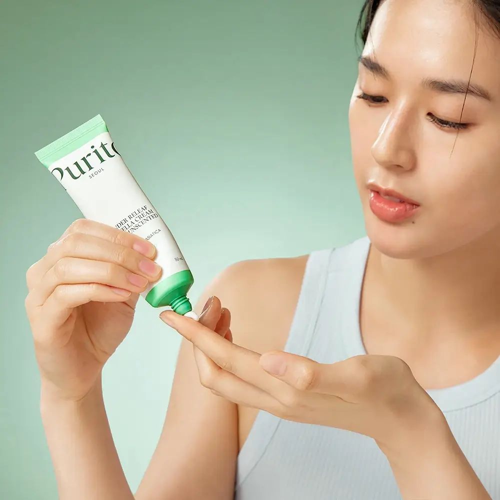 Persona che tiene un tubetto. Scritto: Purito, Wonder Releaf Centella Cream Unscented. Crema applicata sul dito.