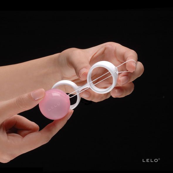 LELO Luna Beads Mini: Sfera rosa con cordino, tenuta da una mano.