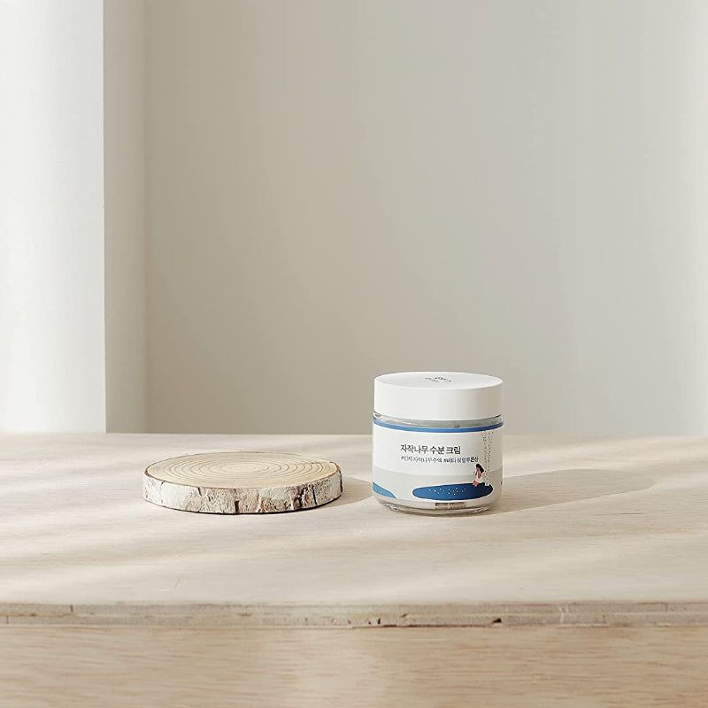 Vasetto di crema con coperchio bianco. Su una fetta di legno. Su sfondo chiaro.