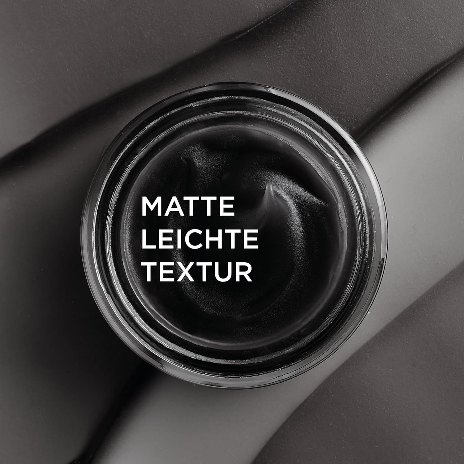 Primo piano della crema nera in un vasetto. Testo: Texture opaca e leggera.