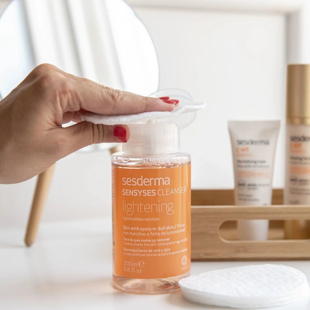 Bottiglia inclinata. Scritta: Sesderma Sensyses Cleanser Lightening. Bottiglia trasparente con liquido arancione.
