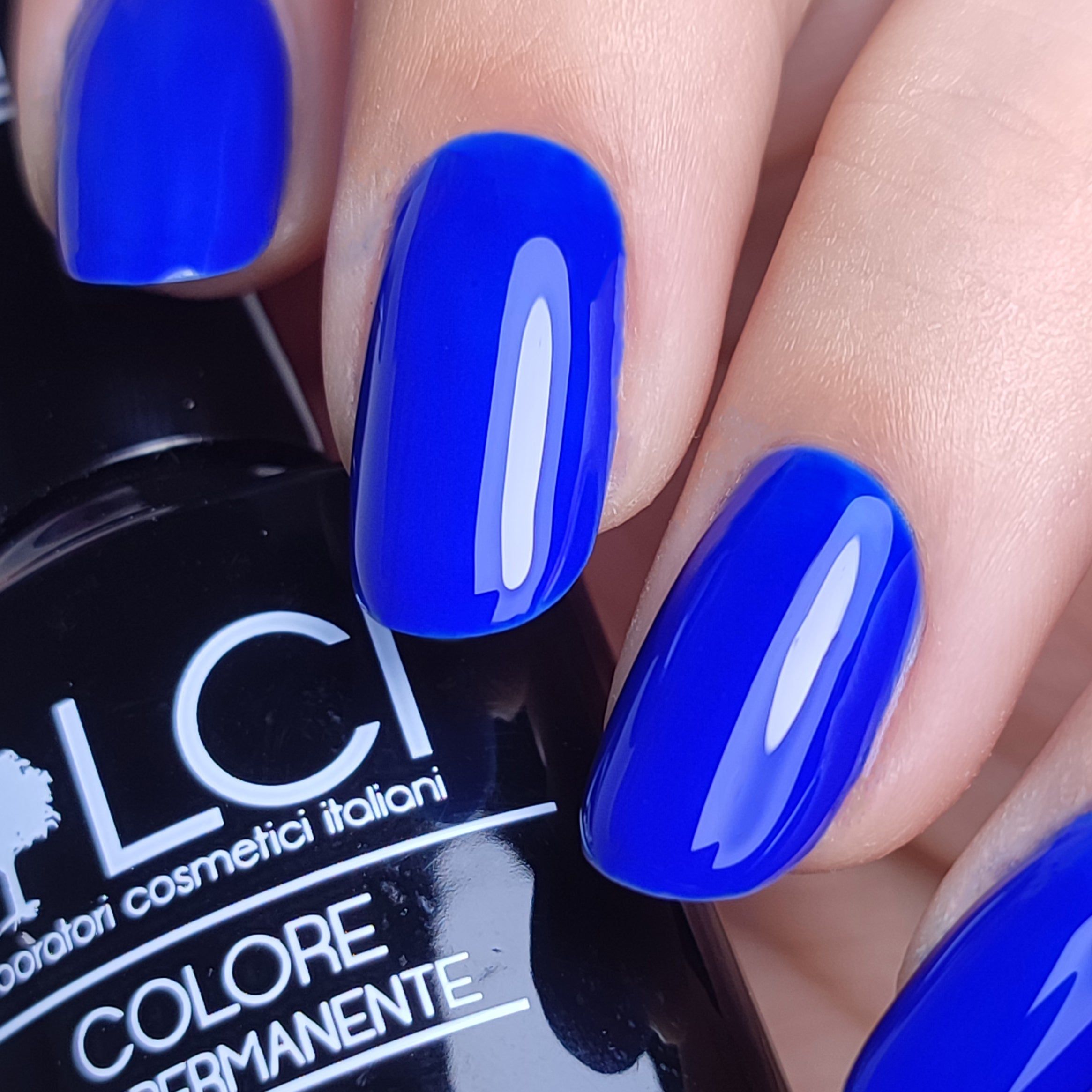 Unghie smaltate di blu. Flacone con scritta LCI e COLORE SEMIPERMANENTE.