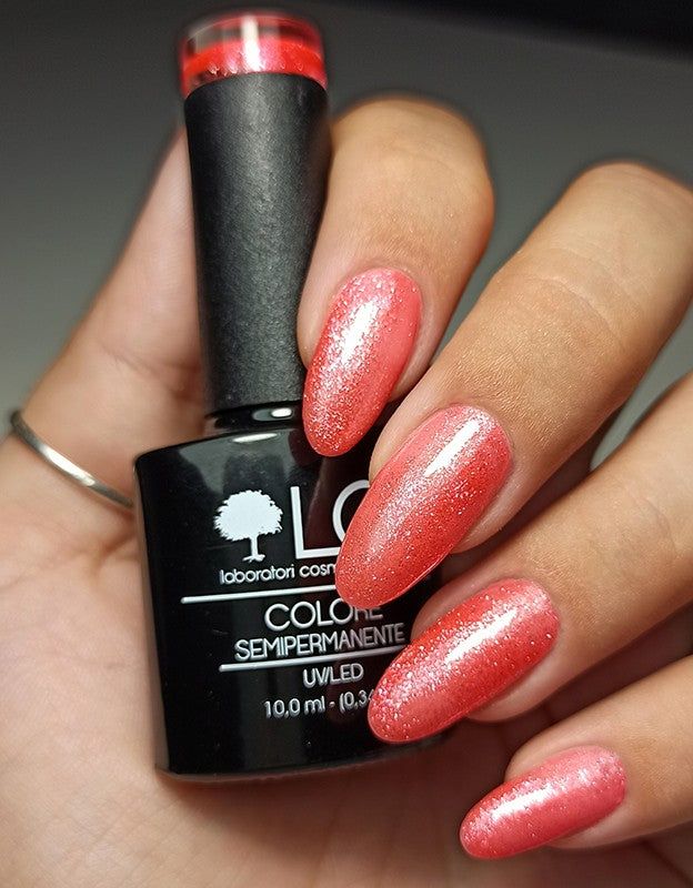 Mano con unghie smaltate rosa arancio. Flacone di smalto accanto. Scritta: LCI, Colore Semipermanente, UVLED.