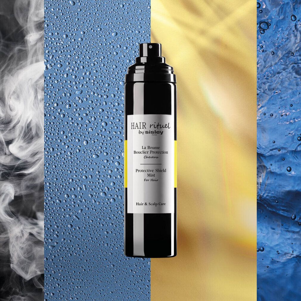 Flacone spray nero con banda gialla. Scritte: HAIR rituel by sisley, La Brume Bouclier Protection, Protective Shield Mist. Sfondo.