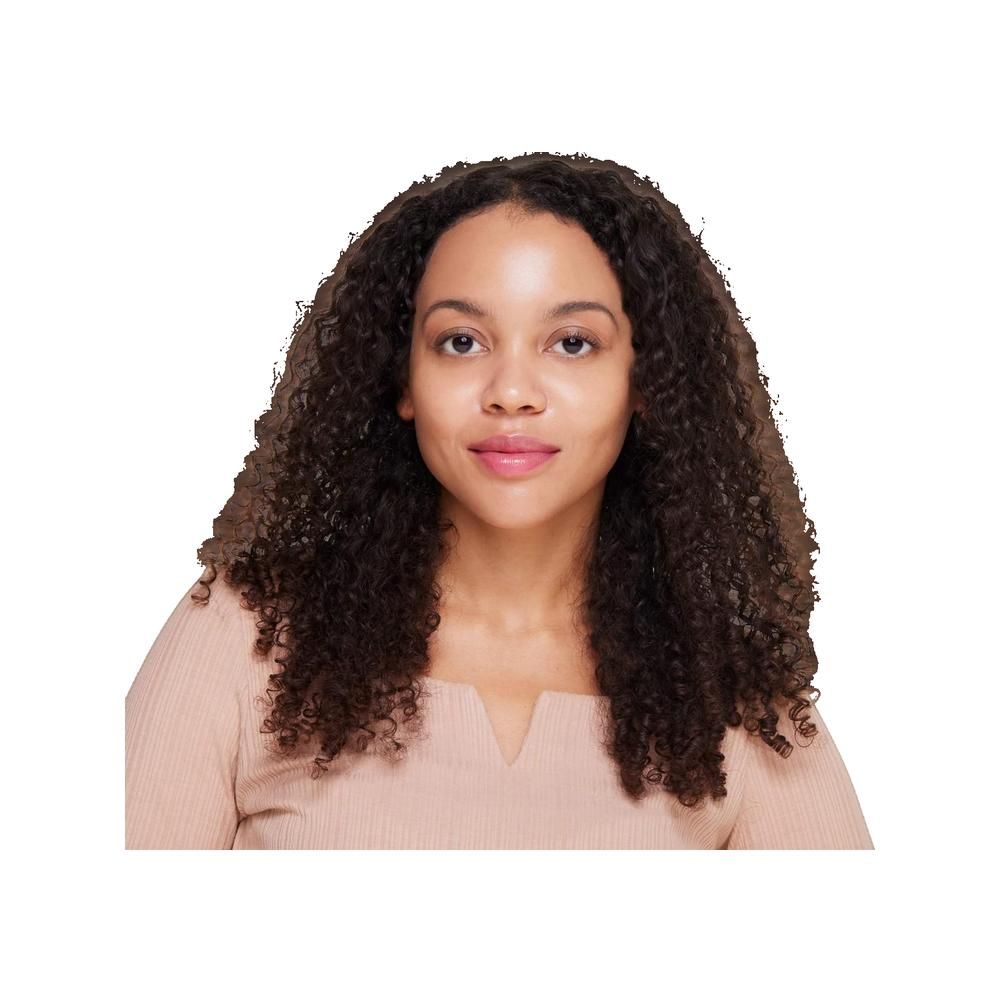 Ritratto di donna con capelli castani ricci e top beige. Guarda direttamente la fotocamera.