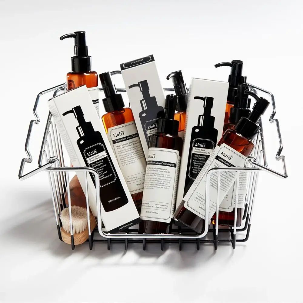 Diverse bottiglie con erogatore nero in un cestino. Nome prodotto: Gentle Black Deep Cleansing Oil.