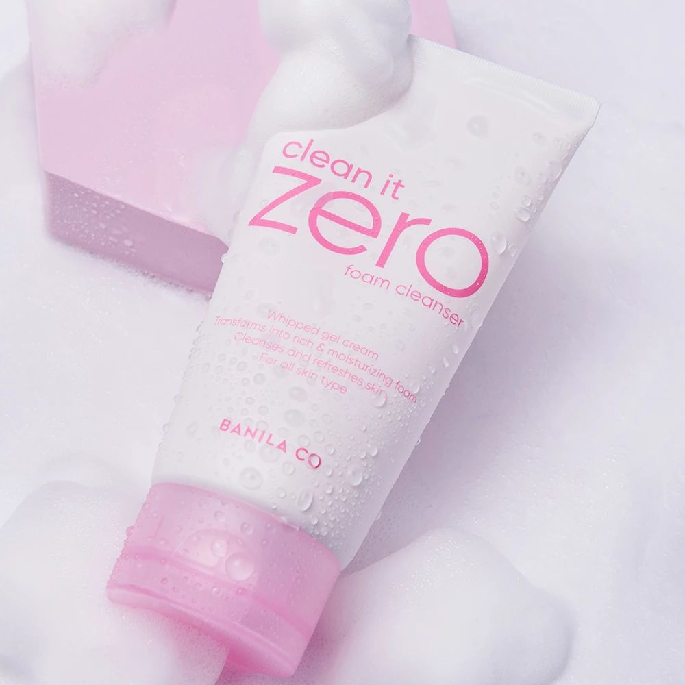 Tubo bianco con dettagli rosa e scritta "clean it zero foam cleanser". Circondato da schiuma. Logo BANILA CO.