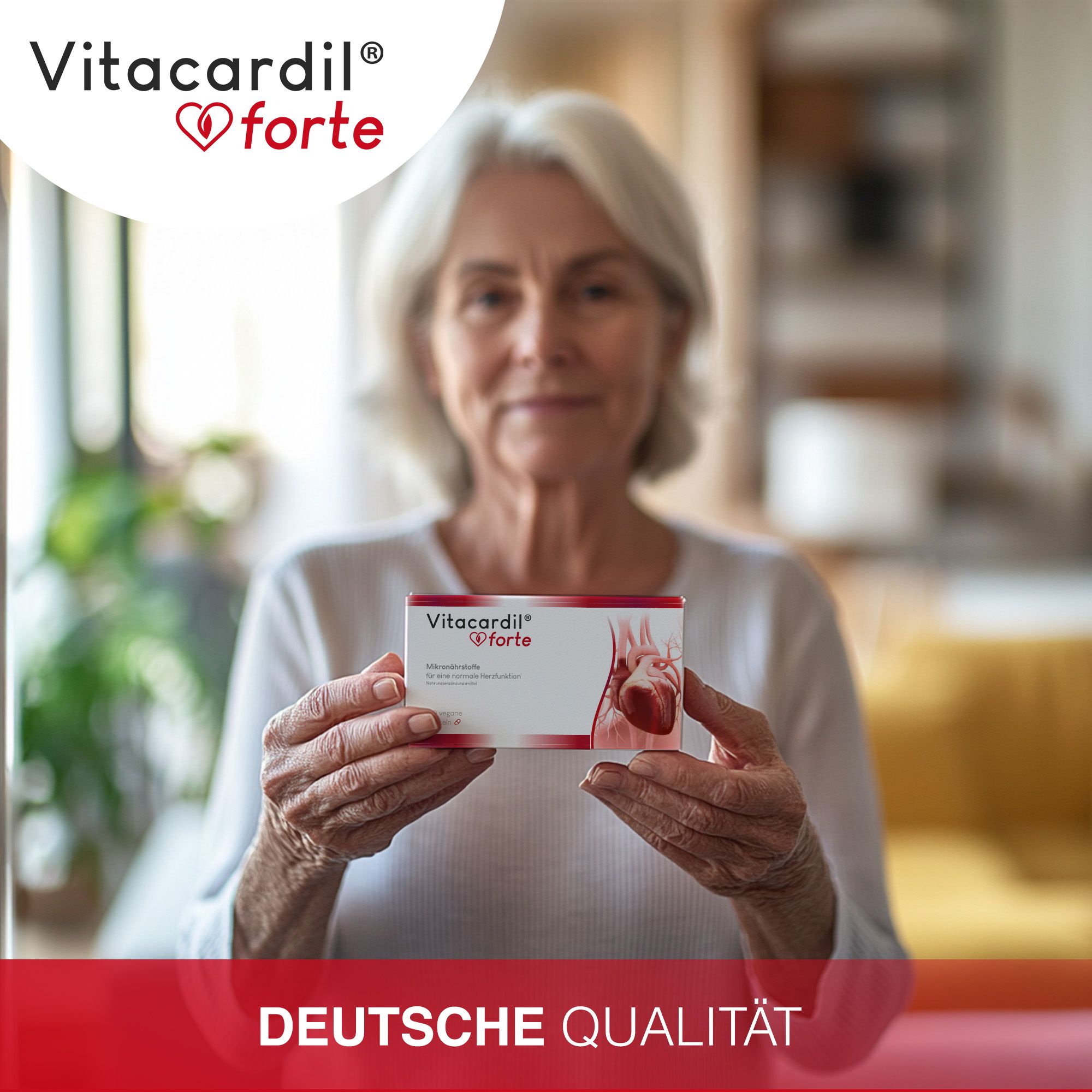 Una donna anziana tiene in mano una confezione di Vitacardil® forte. Sulla confezione è raffigurato un cuore. È visibile la scritta "Deutsche Qualität".