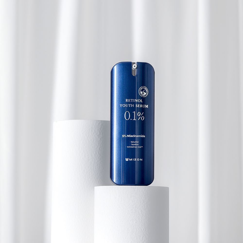 Flacone di siero blu su piedistallo bianco. Scritta: Retinol Youth Serum 0.1%, 5% Niacinamide, MIZON.