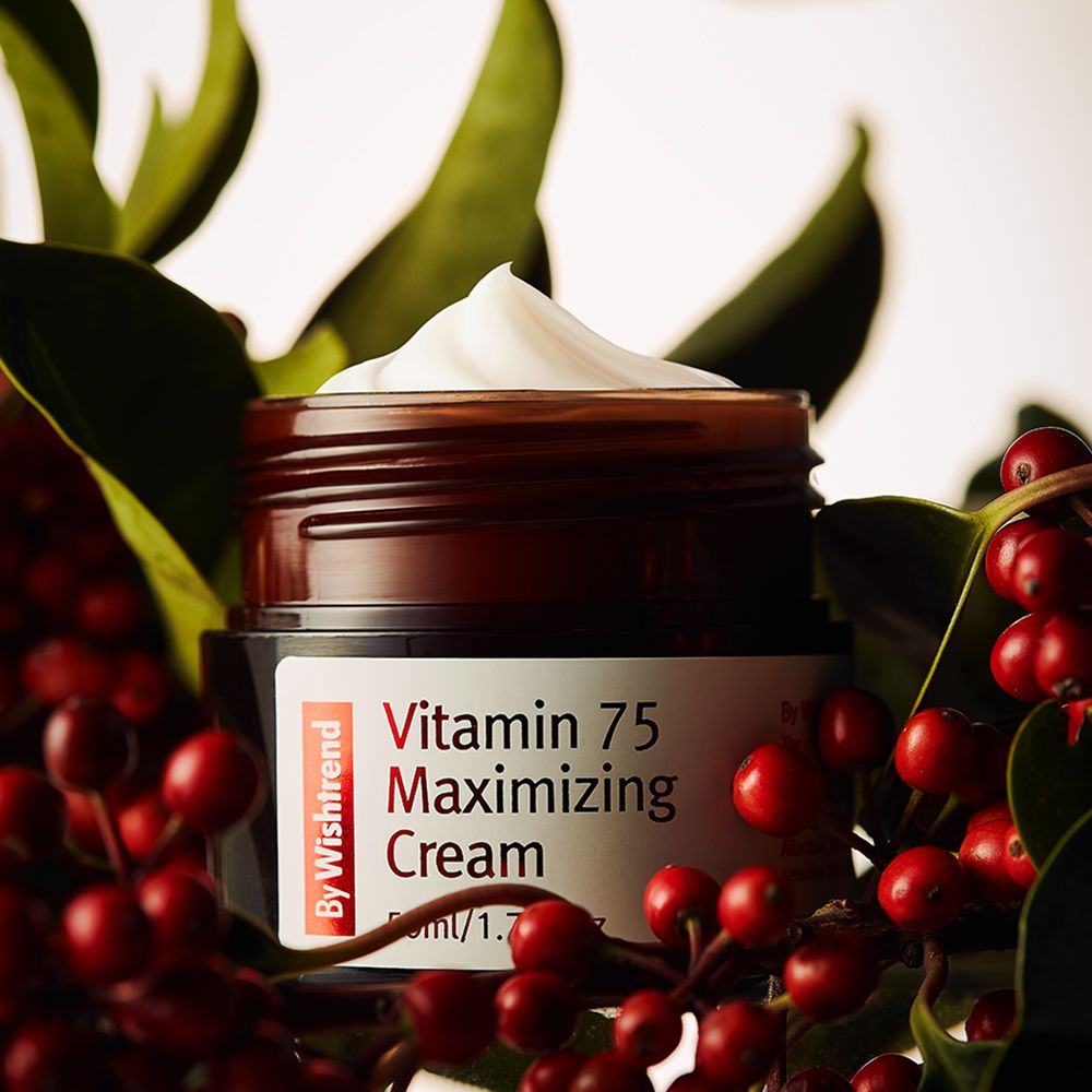 Vaso marrone con crema, circondato da bacche rosse e foglie verdi. Etichetta con testo rosso: Vitamin 75 Maximizing Cream. Marchio: By Wishtrend.