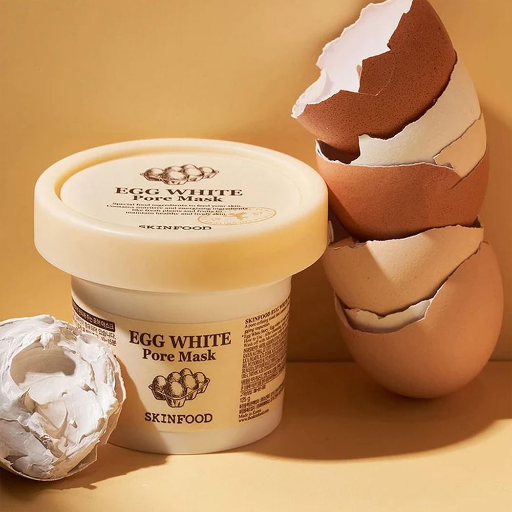 Vasetto con maschera, gusci d'uovo accanto. Scritta: Egg White Pore Mask, Skinfood.