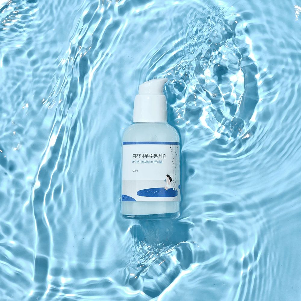 Round Lab Birch Juice Serum, 50ml, in flacone con erogatore in mezzo a onde d'acqua.