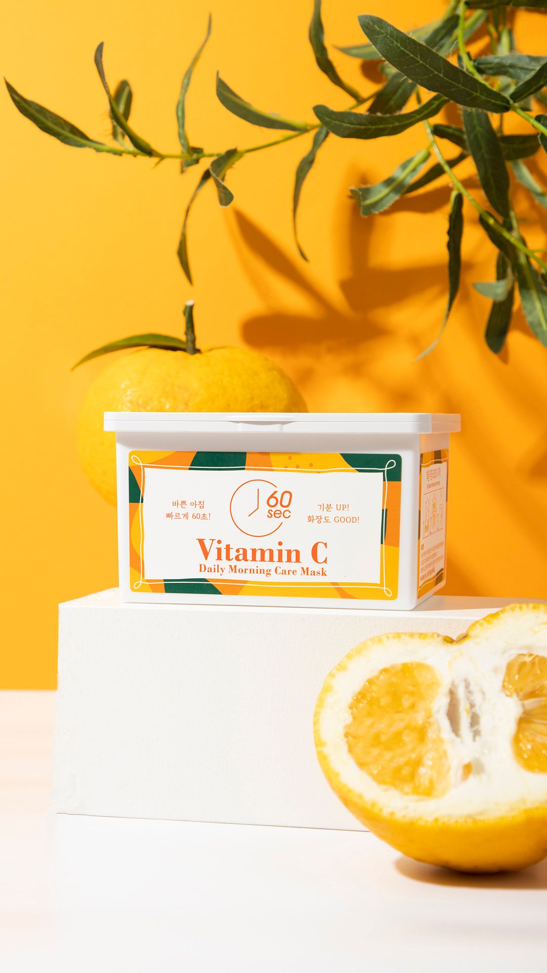 Contenitore di maschere alla vitamina C su piedistallo. Sfondo giallo. Agrumi. Scritta: Vitamin C Daily Morning Care Mask.