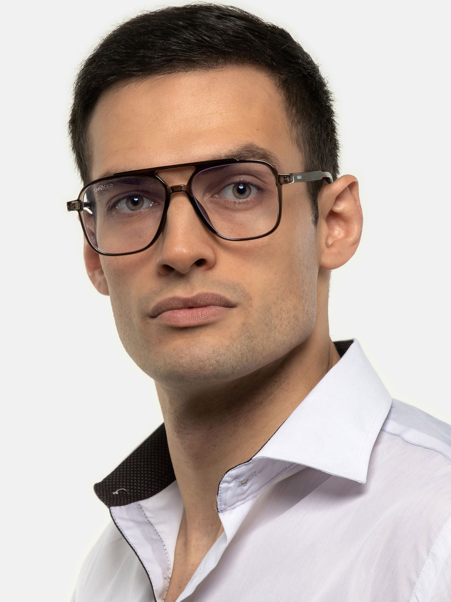 Uomo con occhiali grigi. Montatura rettangolare, doppio ponte. Design unisex. Camicia bianca.