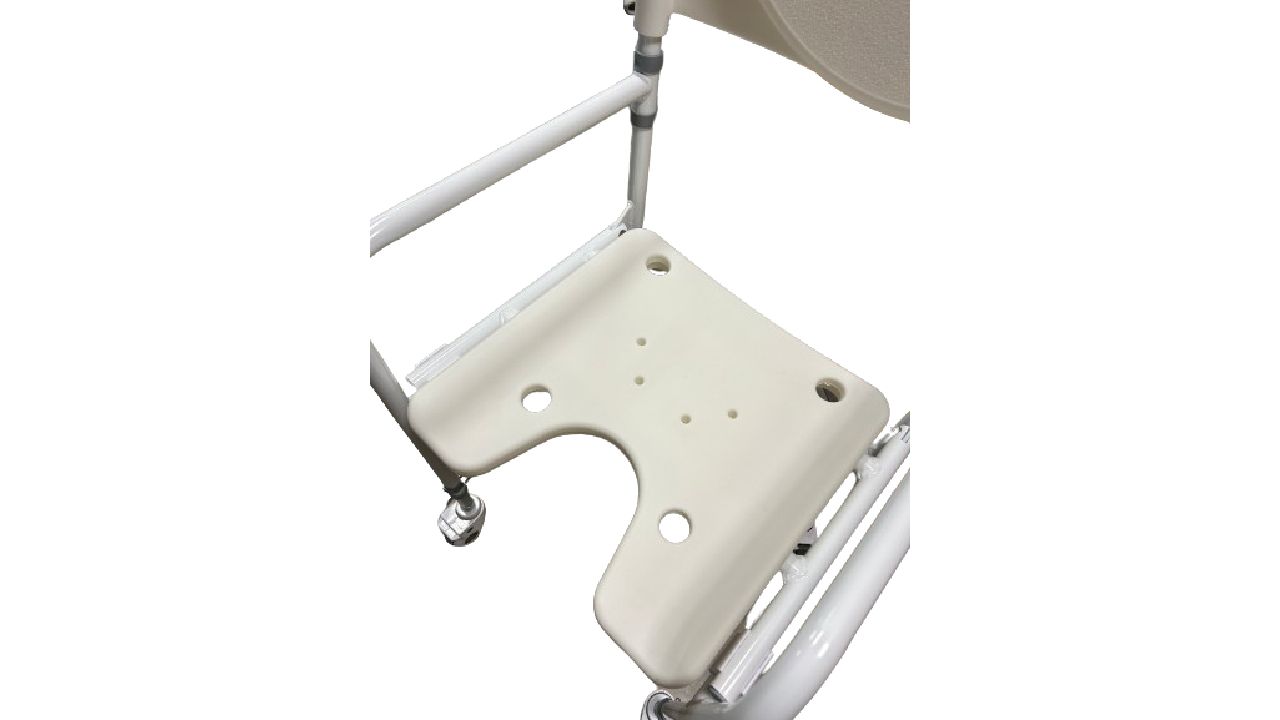 Primo piano della seduta di una sedia doccia con ruote. Beige, con intaglio e fori. Telaio e braccioli bianchi.
