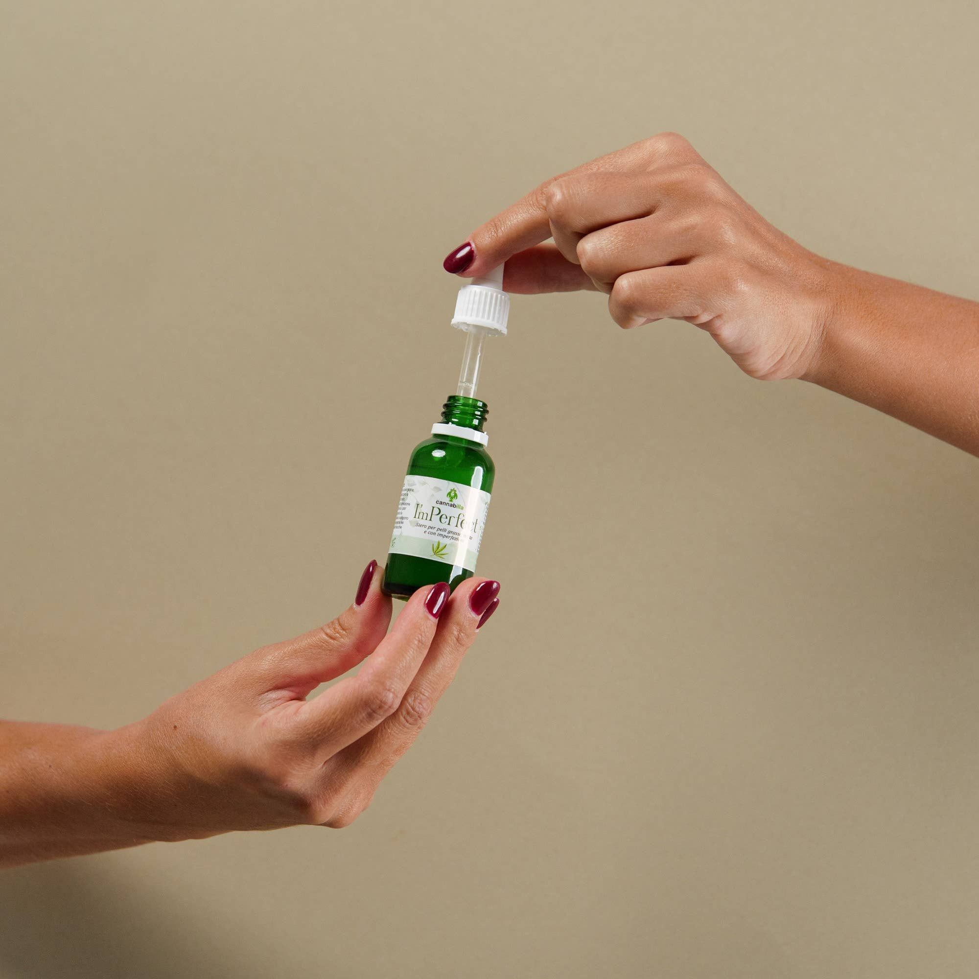 Due mani tengono un flacone verde con contagocce. Scritto: ImPerfect, Siero Viso Purificante alla Canapa.