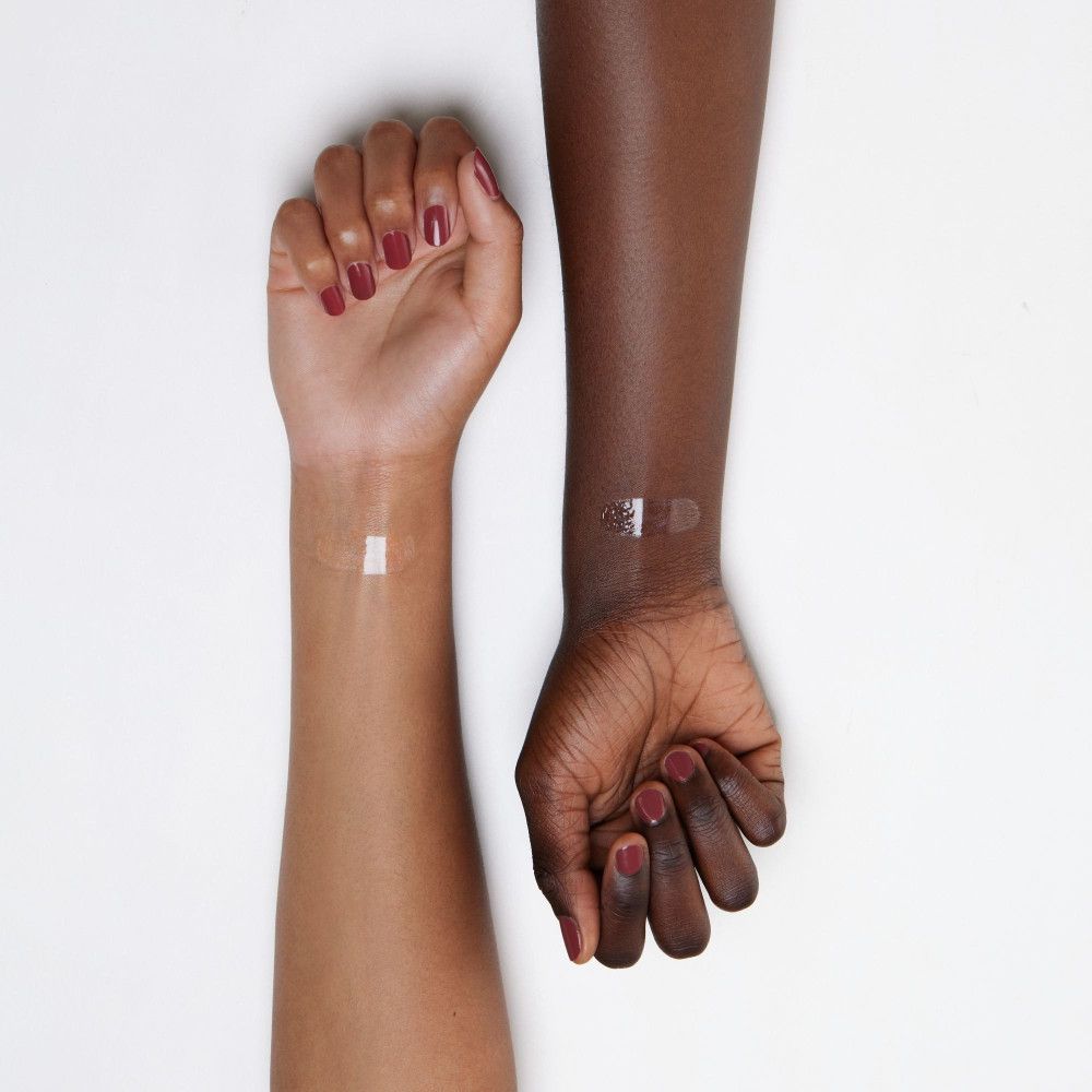 Due braccia con diverse tonalità di pelle. Una striscia di lucidalabbra trasparente è applicata su ogni polso.