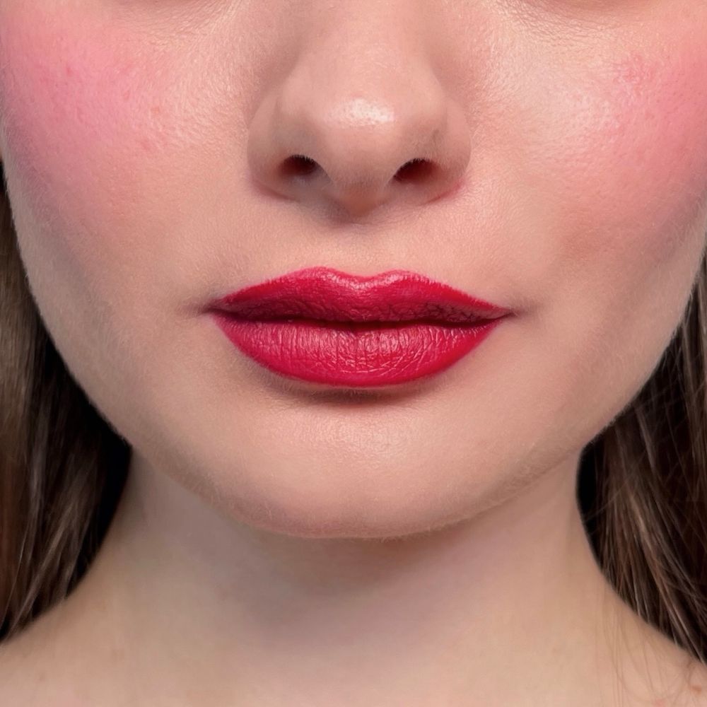 Primo piano di labbra con rossetto rosso e guance arrossate. Tonalità della pelle.