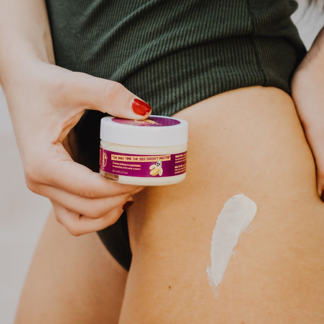 Persona che tiene un contenitore di crema. Traccia di crema visibile sulla pelle.