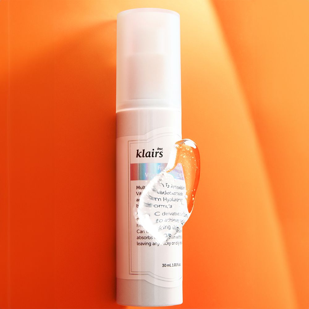 Flacone di siero bianco con erogatore a spruzzo. Goccia di siero sul lato. Scritta: klairs. Sfondo arancione.