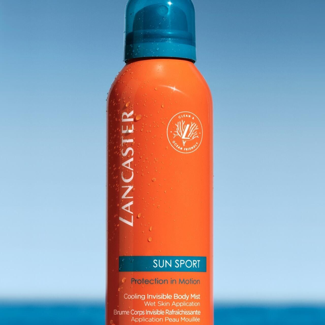 Flacone spray arancione con tappo blu. Scritte: LANCASTER, SUN SPORT. Logo vegano. Nebbia corpo invisibile rinfrescante.
