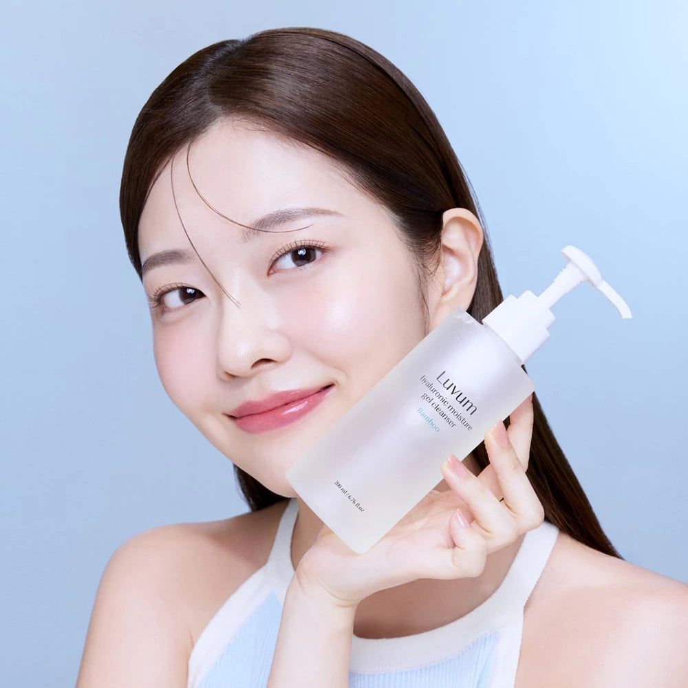Donna tiene in mano flacone trasparente con dosatore bianco. Sul flacone si legge "Luvum Hyaluronic moisture gel cleanser".