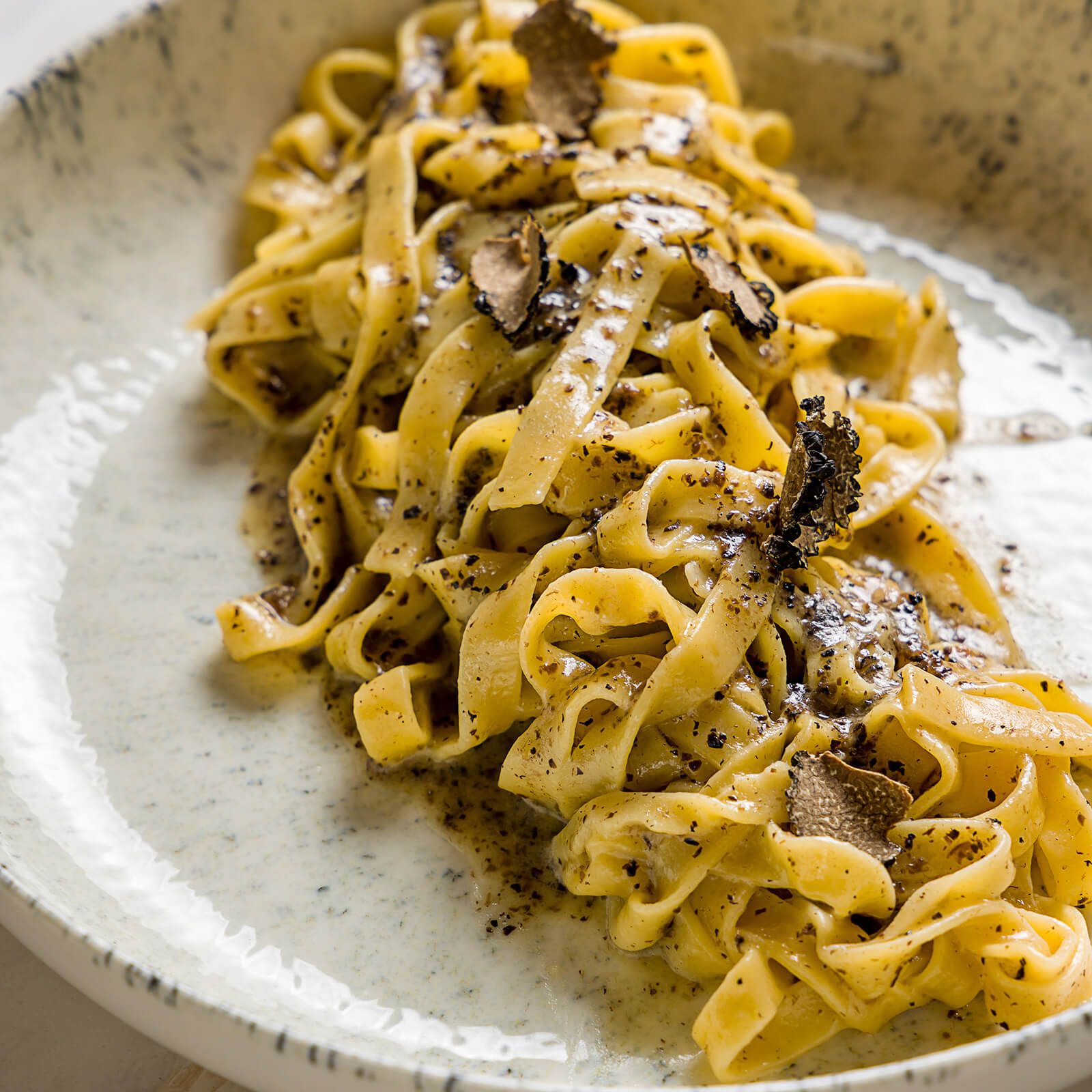 Tagliatelle al tartufo su un piatto bianco. Salsa e scaglie di tartufo.