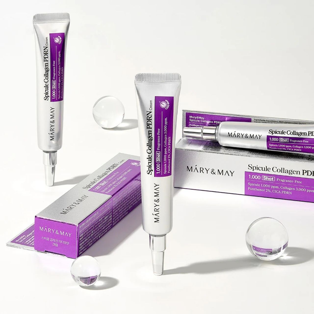 Diversi tubi e scatole di Mary&May Spicule Collagen PDRN Cream con sfere di vetro.