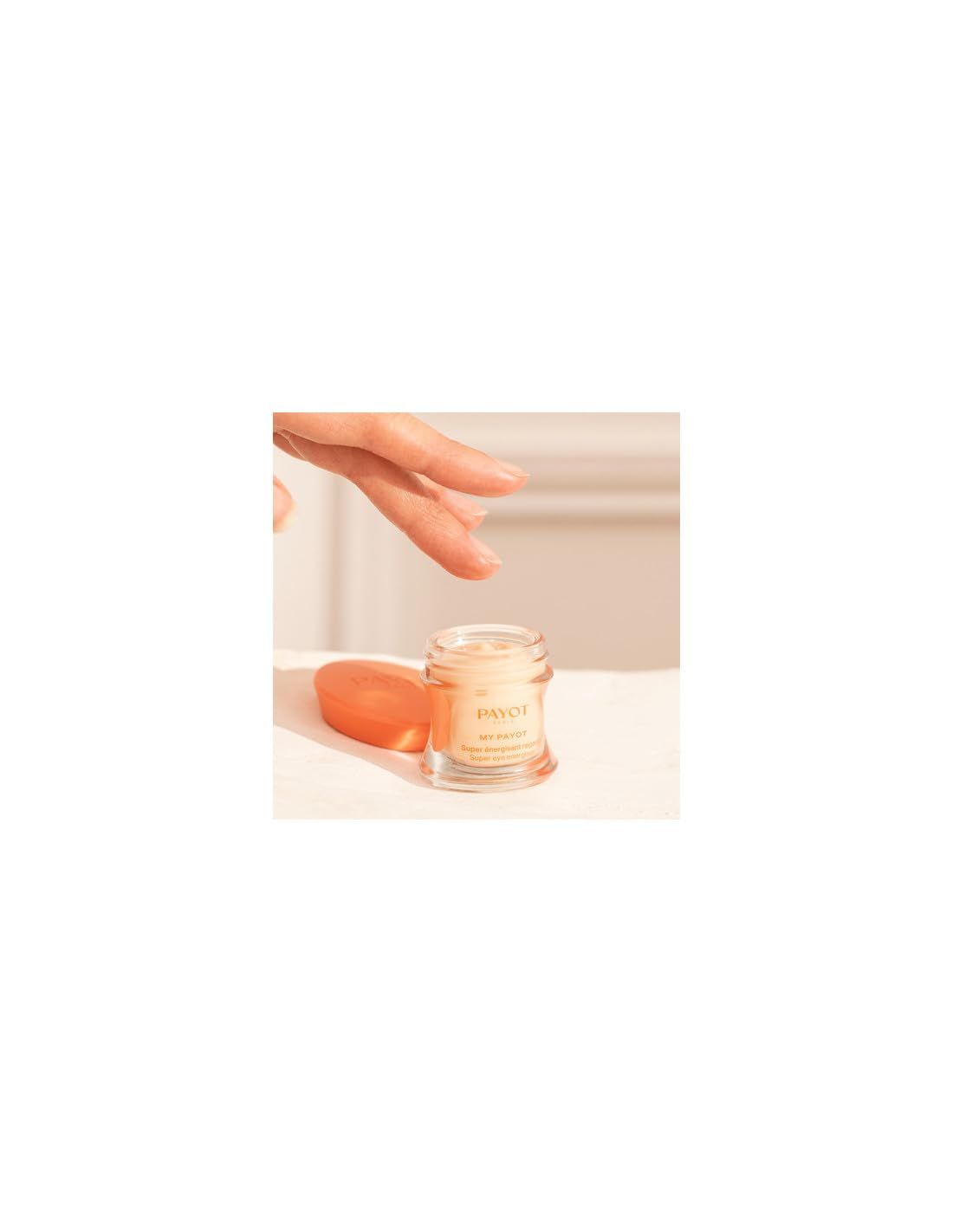 Vasetto di vetro con crema, accanto una spugna arancione. Una mano tocca il vasetto.