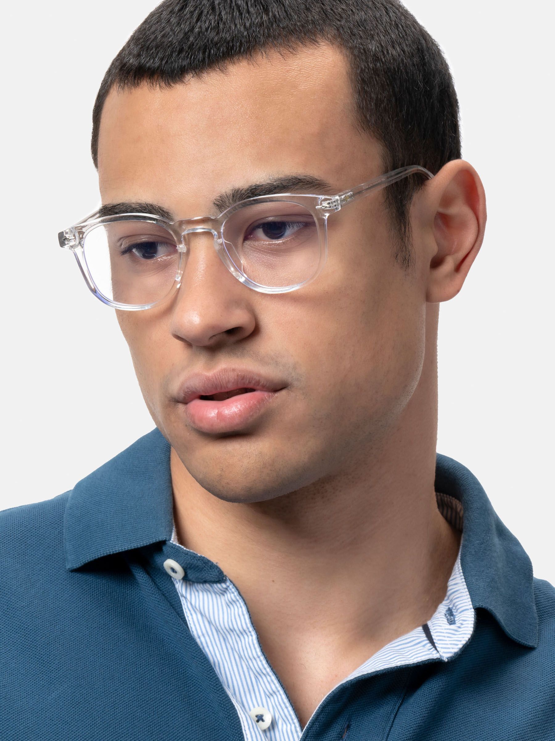 Uomo con occhiali trasparenti. Gli occhiali hanno una montatura quadrata. L'uomo indossa una polo blu.