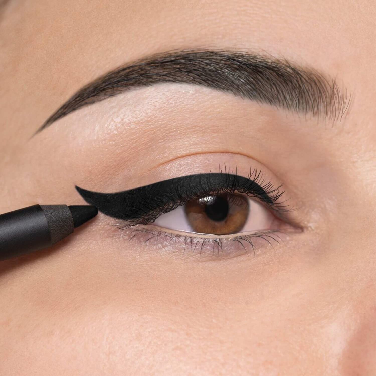 Occhio con eyeliner nero. Matita occhi in uso. Occhi marroni, sopracciglia scure.