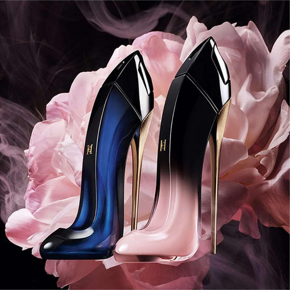 Due flaconi di profumo a forma di scarpa. Sfumatura nero-rosa e blu-nero, tacco dorato. Davanti a fiori rosa.