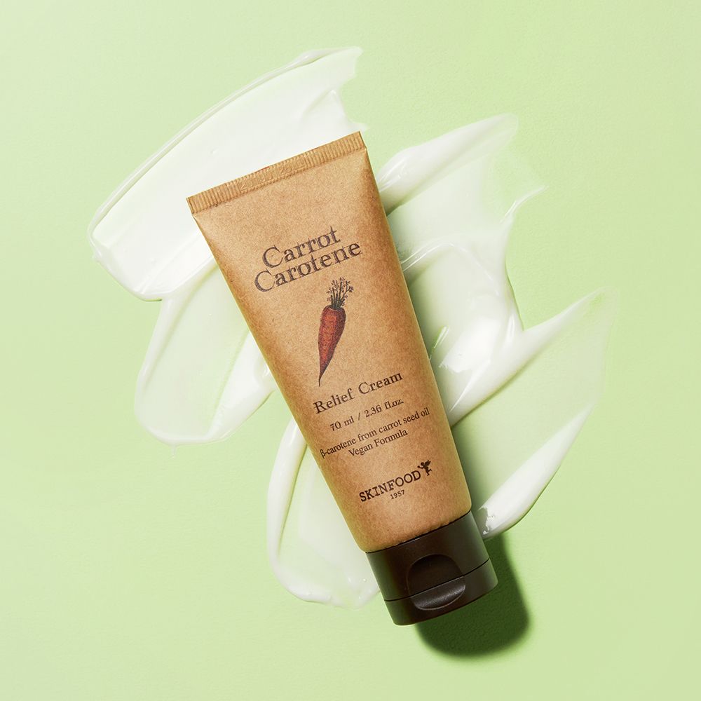 Tubo beige con tappo marrone su sfondo verde con crema. Scritta: Carrot Carotene, Relief Cream, SKINFOOD.