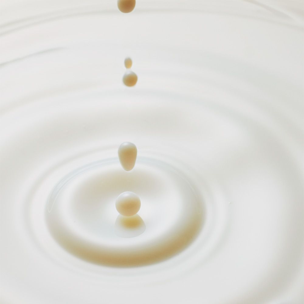 Gocce cadono in un liquido lattiginoso, creando cerchi concentrici.