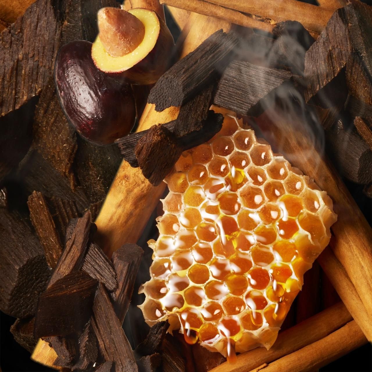 Primo piano di favo, pezzi di legno, bastoncini di cannella e un frutto. Sale vapore.