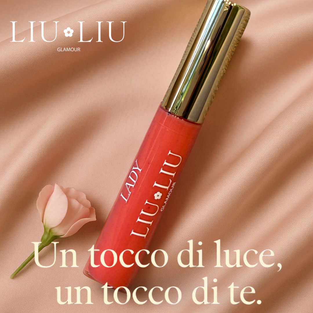 Tubo di lucidalabbra con tappo dorato. Scritta: LADY LIU LIU GLAMOUR. Sfondo rosa con fiore.