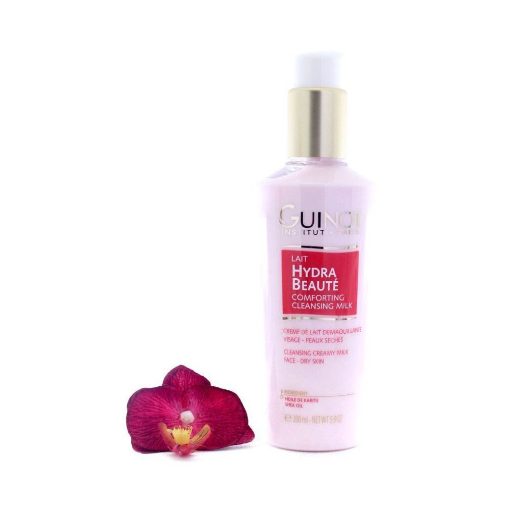 Flacone rosa con tappo dorato. Scritta: Guinot, Lait Hydra Beauté, Cleansing Milk. Un'orchidea è accanto.