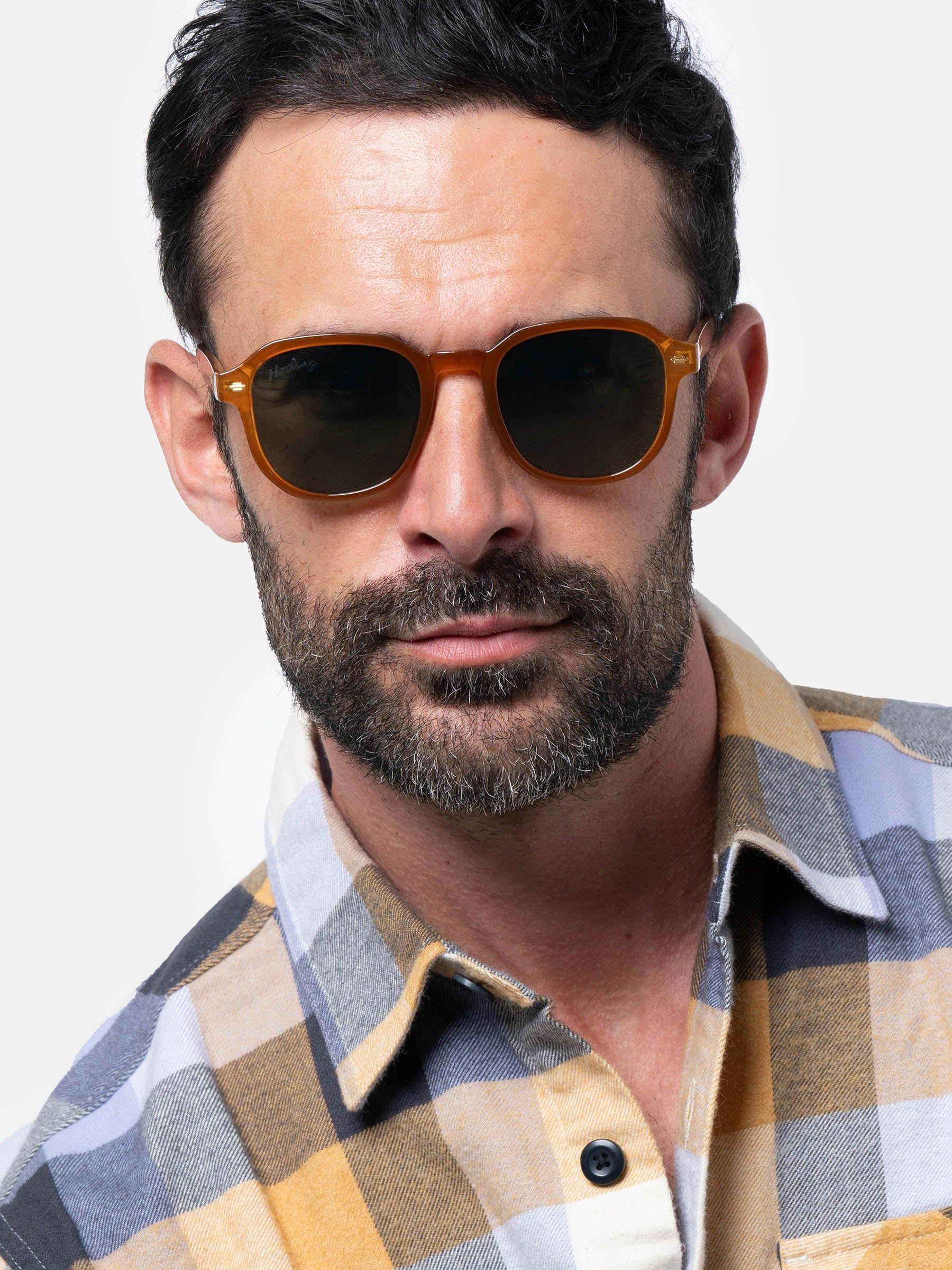 Uomo con occhiali da sole marroni con lenti verdi. Il marchio Herling è visibile sulla lente.