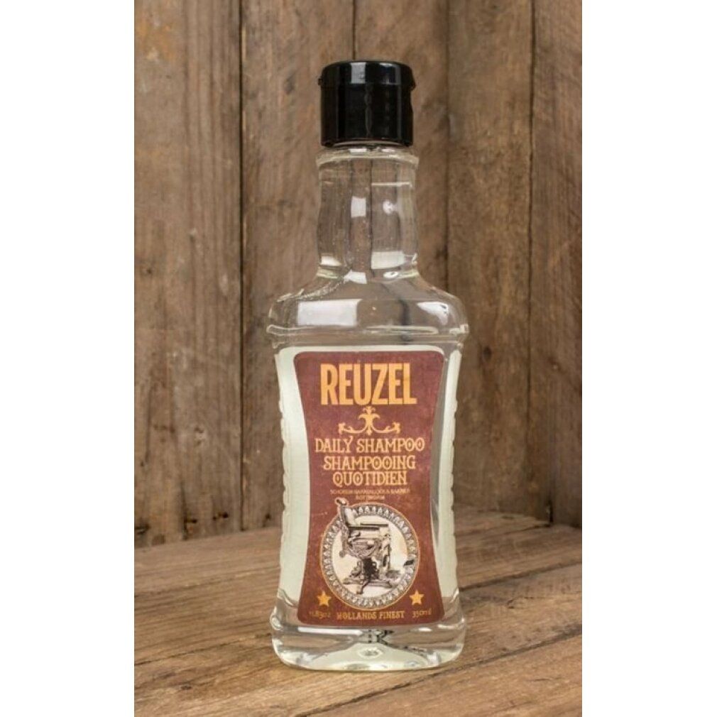 Flacone trasparente Reuzel Daily Shampoo. Etichetta marrone, tappo nero. Davanti a sfondo in legno.