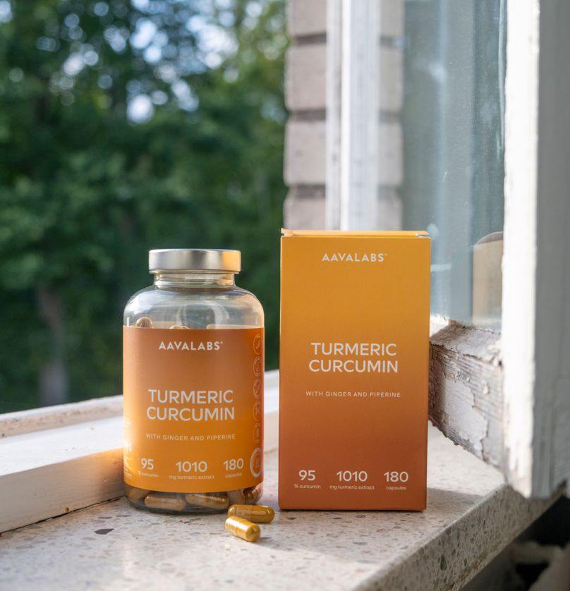 Flacone e scatola di capsule. Scritta: Turmeric Curcumin, con zenzero e piperina. 180 capsule.