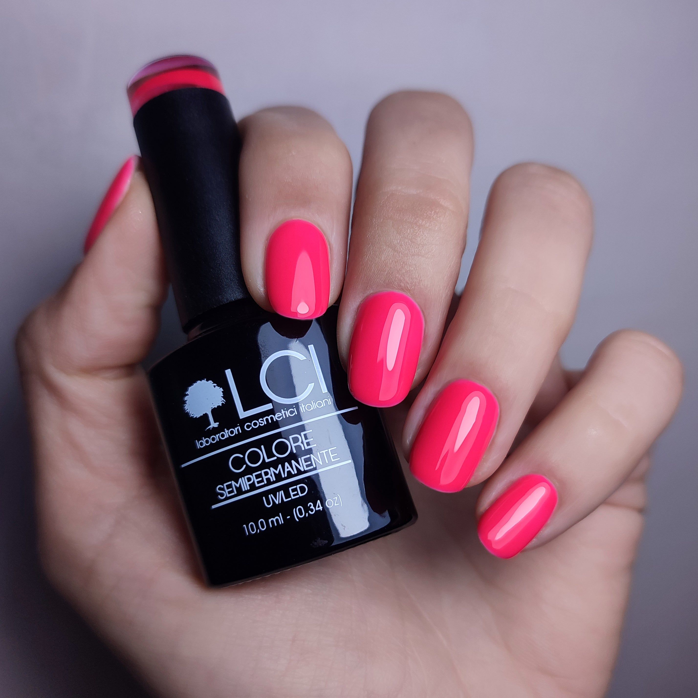 Mano con unghie smaltate rosa. Flacone con scritta LCI, Colore Semipermanente, UVLED.