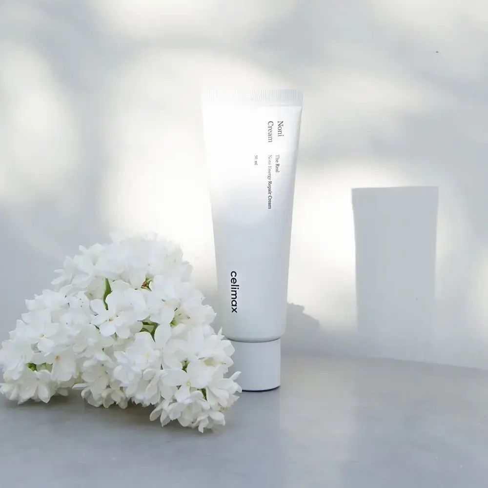 Tubo bianco con nome e marchio del prodotto. Fiori bianchi e sfondo chiaro. 50 ml.