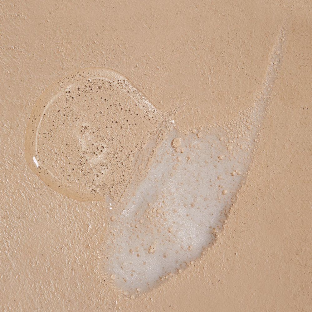 Texture di gel doccia su sfondo beige. Una traccia trasparente e una traccia con particelle.